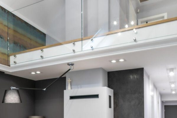 Salon z kominkiem pod antresolą ze szklaną balustradą