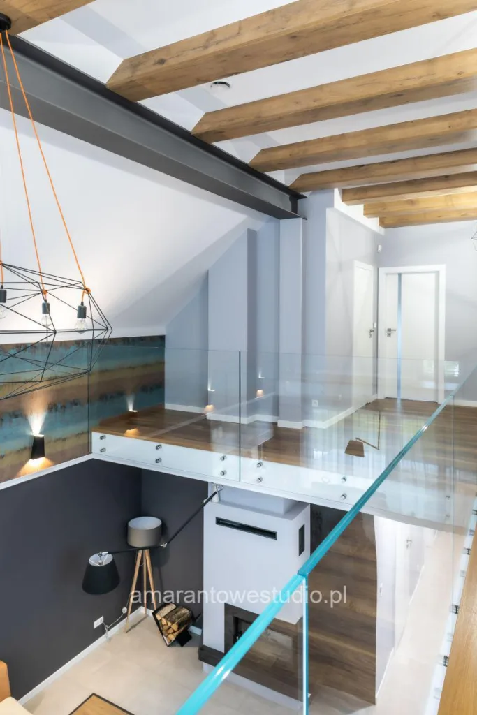 Widok z antresoli na salon, drewniane belki i lampy druciane