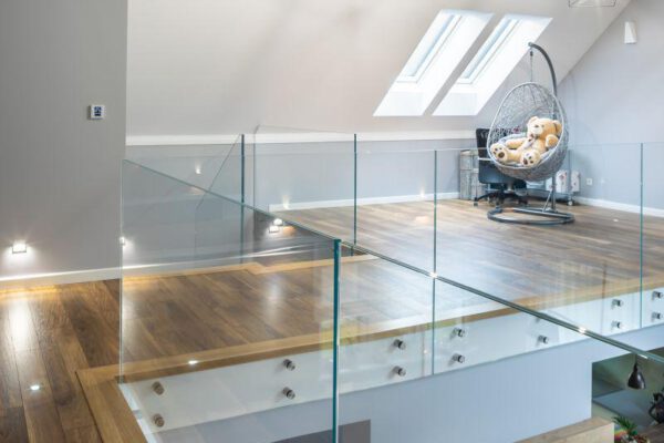 Antresola ze szklaną balustradą, fotelem wiszącym i oknami dachowymi