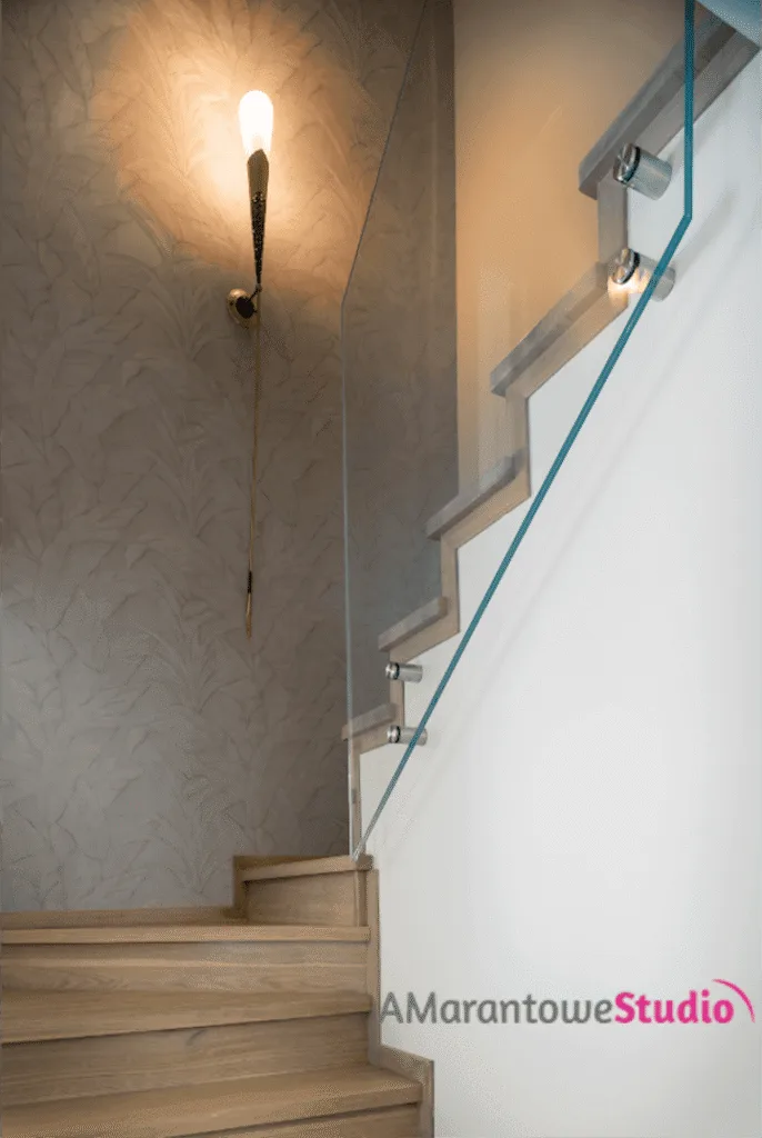 Drewniane schody ze szklaną balustradą i kinkietem na ścianie