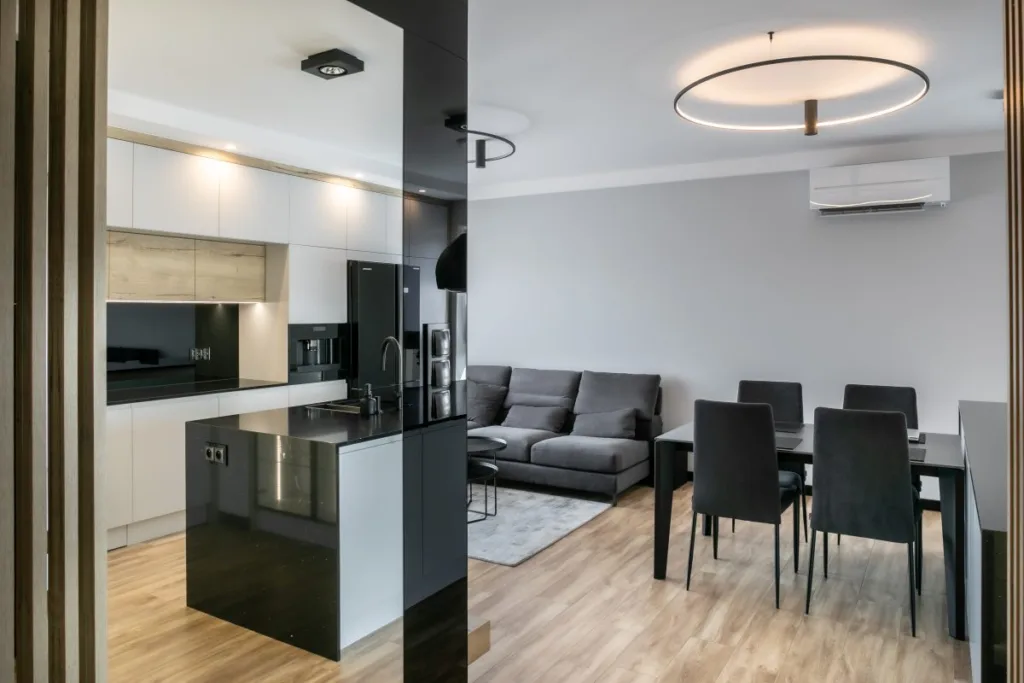Kuchnia z czarną wyspą, jadalnia i szara sofa w salonie
