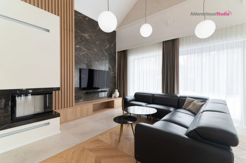 Salon z czarną skórzaną sofą, kominkiem i dębowymi lamelami