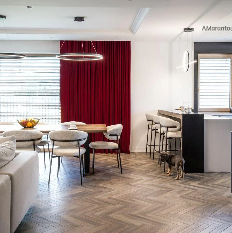 Salon z jasną sofą, czerwonymi zasłonami i jadalnią w tle