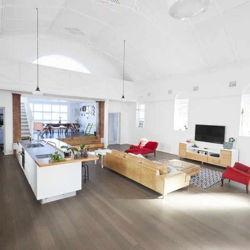 Architekt wnętrz prezentuje otwartą przestrzeń z podłogą drewnianą, białym sufitem i wyspą kuchenną